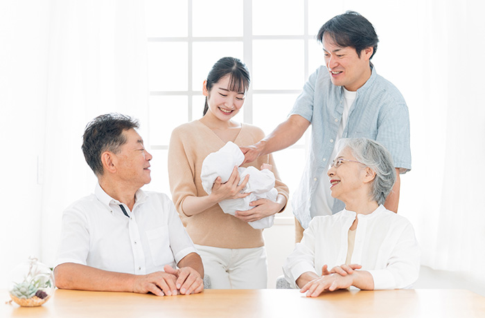 赤ちゃんを家族が笑顔で取り囲む写真
