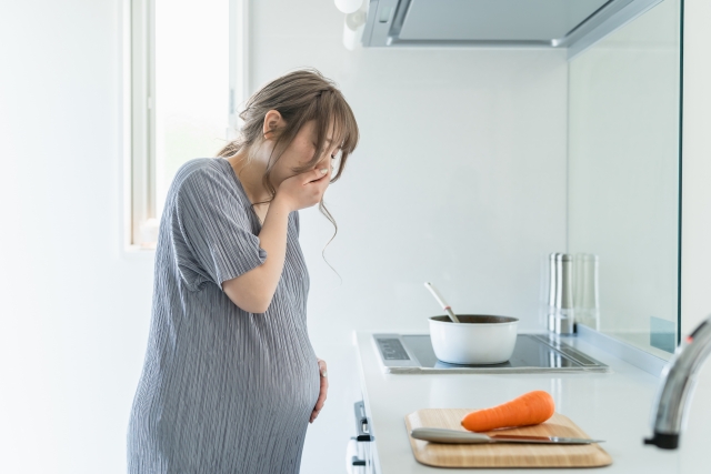 キッチンで吐き気・悪阻・嘔吐に苦しむ妊婦
