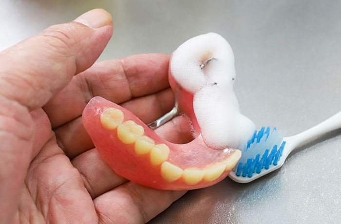 入れ歯を歯ブラシで洗浄する様子