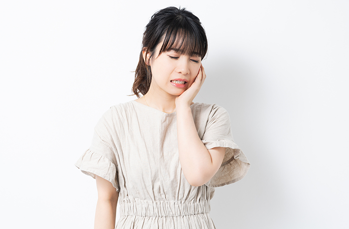 虫歯がある側の頬を手で抑える女性