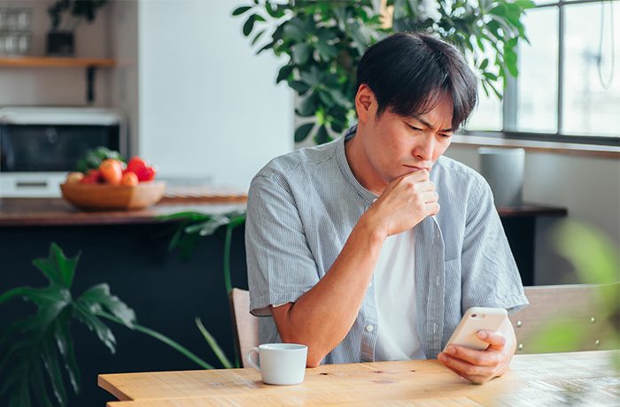 虫歯になり不安でスマホで調べる男性